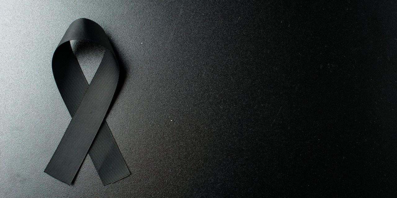 top view of black bow as mourning symbol on dark wall scaled 1 1280x640